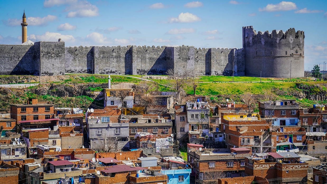 The ancient city walls of Diyarbakir tower over a bustling urban landscape.