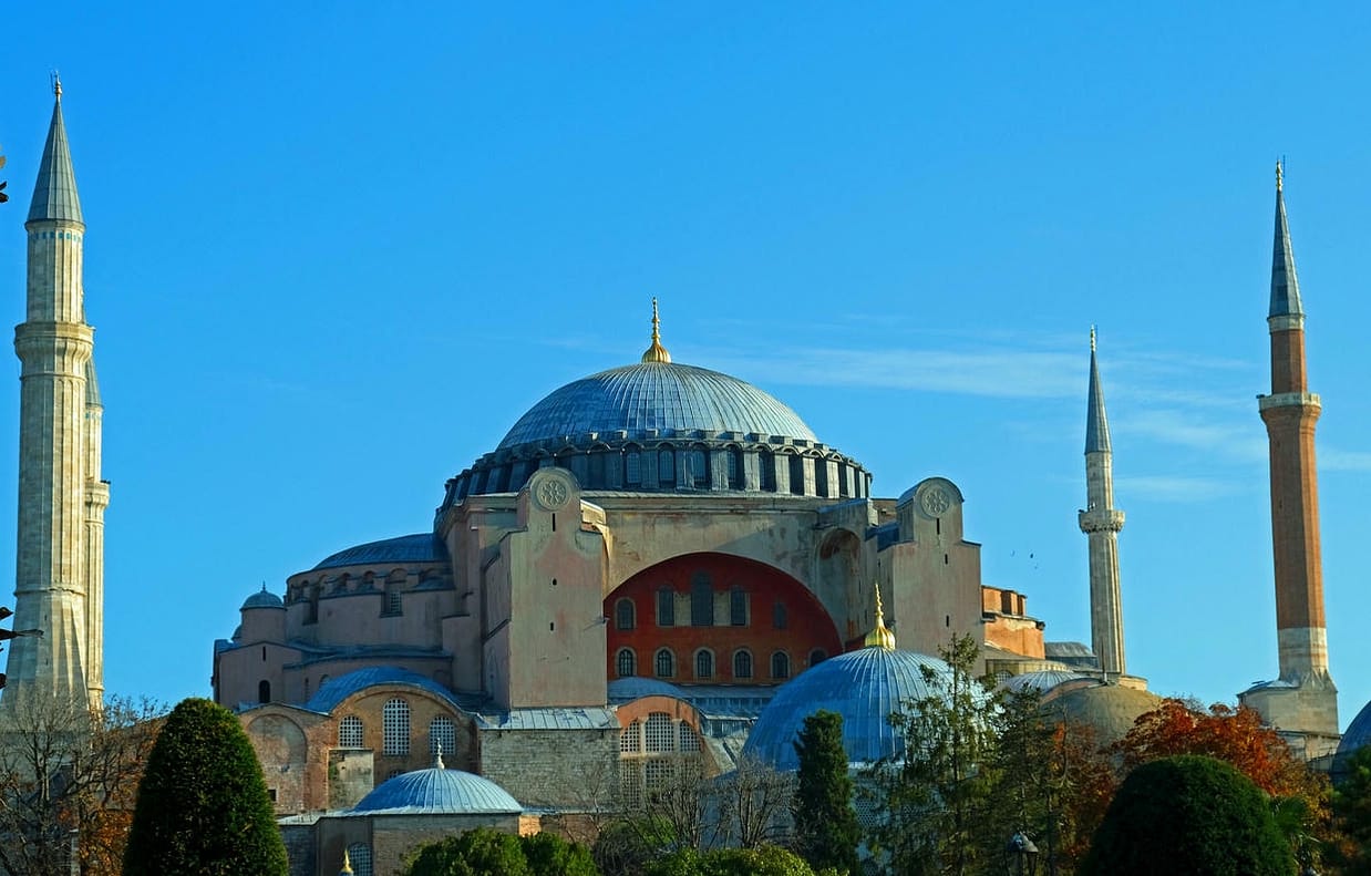 The majestic Hagia Sophia Mosque in Istanbul stands under a bright blue sky, highlighting its historical significance.