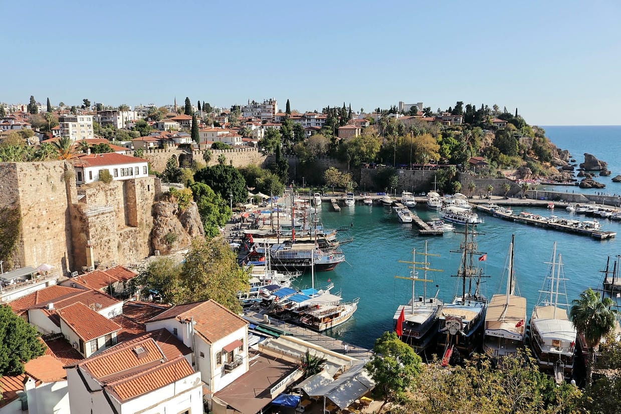 A stunning aerial view of Antalya's historic harbor with yachts and surrounding architecture on a sunny day.