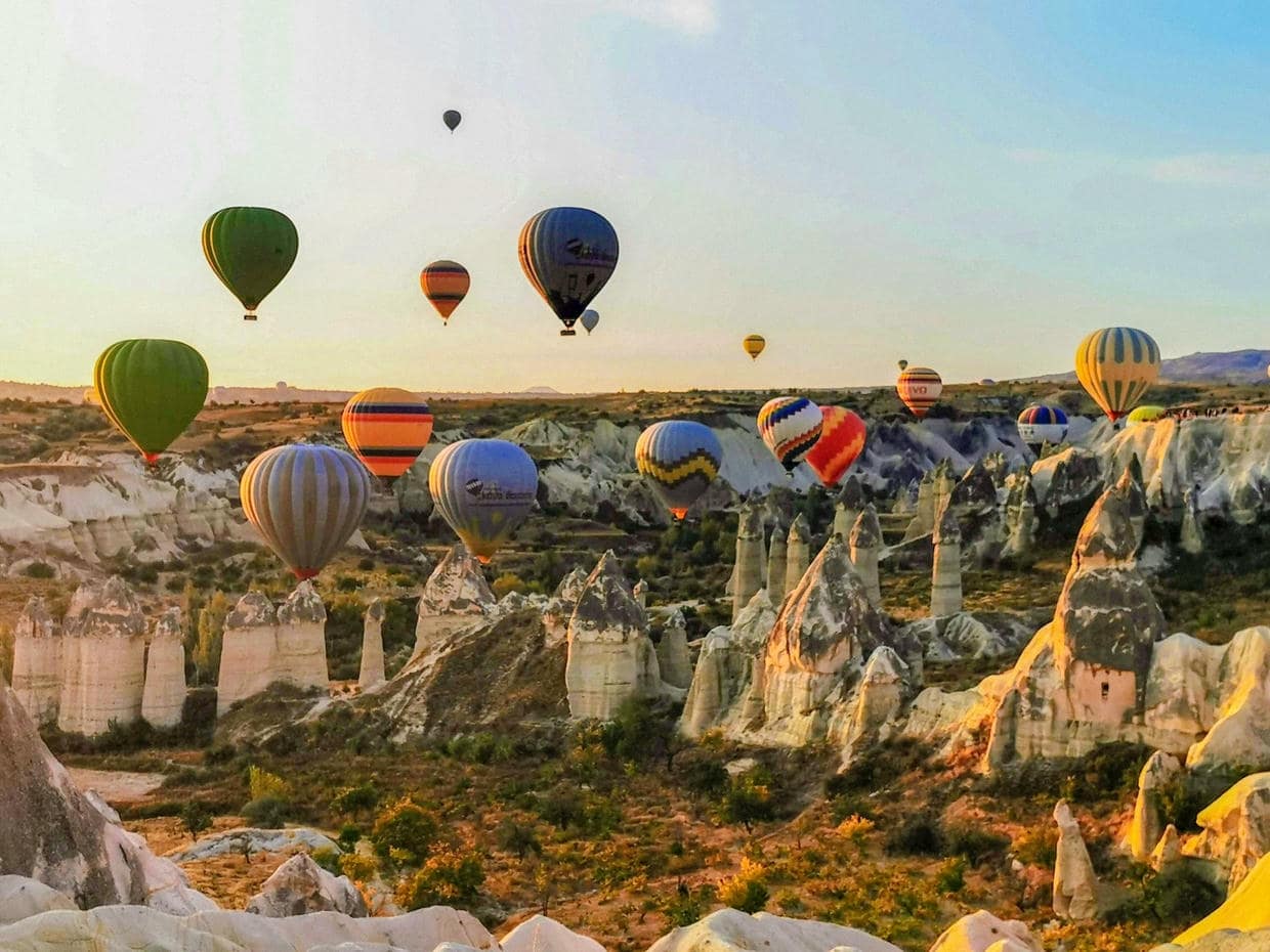 Stunning view of hot air balloons soaring over the unique rock formations of Cappadocia at sunrise.